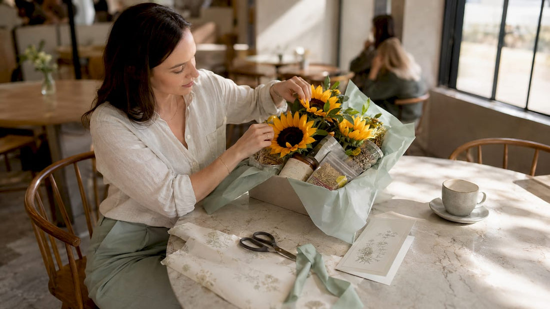 Woman arranging birthday floral hamper at wooden table